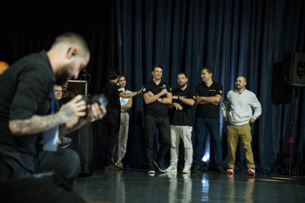 Lucas Has agachado, fotografando um grupo no palco