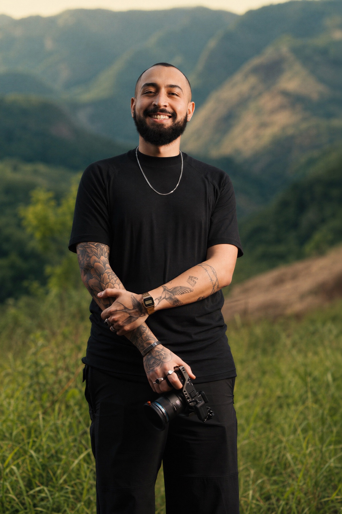 Lucas Has sorrindo, com a câmera na mão e montanhas ao fundo